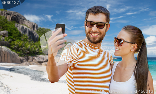 Image of happy couple taking selfie by smartphone on beach