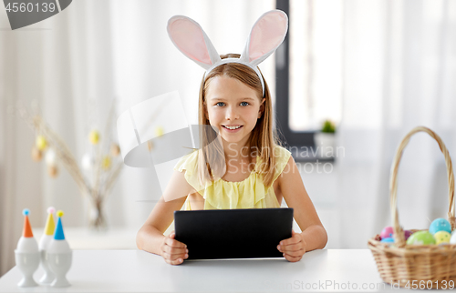 Image of happy girl with tablet pc and easter eggs at home
