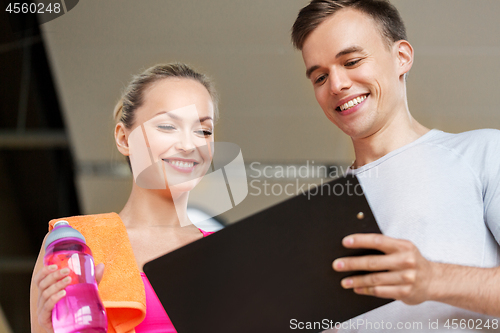 Image of woman and personal trainer with clipboard in gym