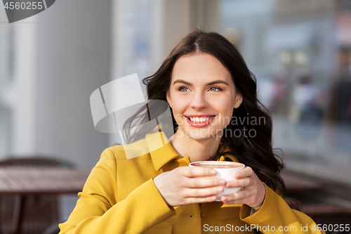 Image of teenage girl drinking hot chocolate at city cafe