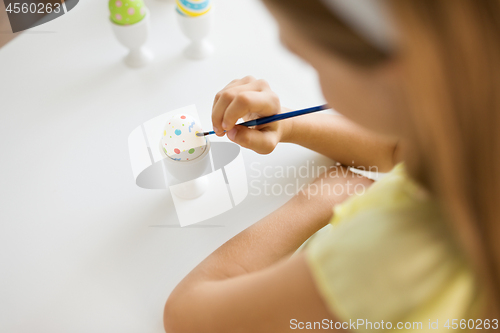 Image of close up of girl coloring easter egg by paintbrush