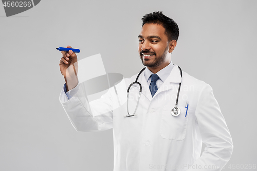 Image of smiling indian male doctor with marker