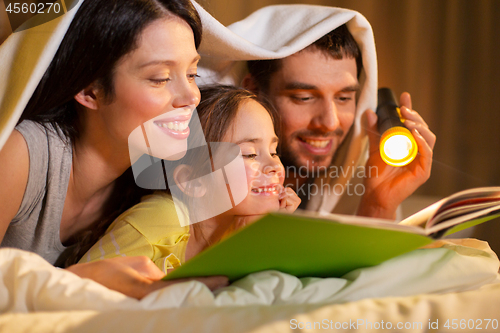 Image of happy family reading book in bed at night at home