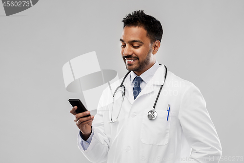 Image of smiling indian male doctor with smartphone