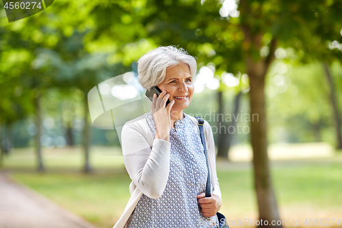 Image of senior woman calling on smartphone in summer park