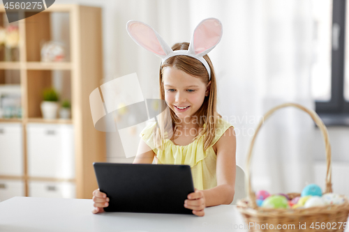 Image of happy girl with tablet pc and easter eggs at home