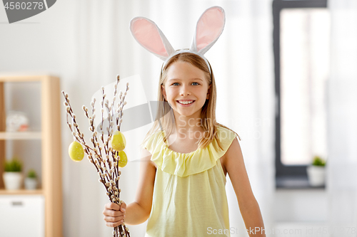 Image of girl with willow decorated by easter eggs at home