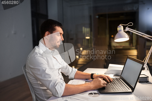 Image of businessman with laptop working at night office