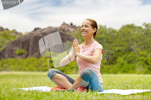 Image of happy woman meditating in exotic summer park