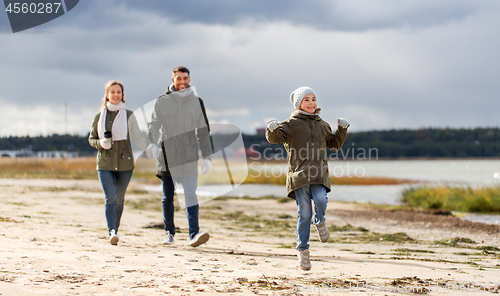 Image of happy family walking along autumn beach