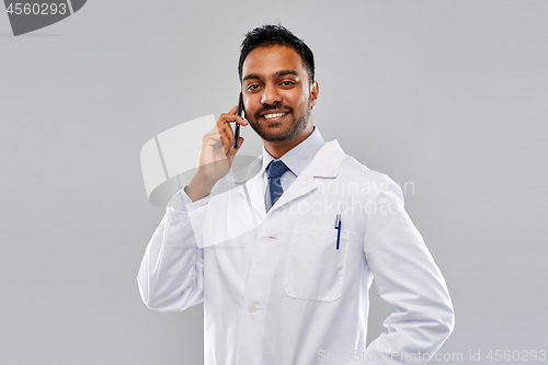 Image of smiling indian male doctor calling on smartphone