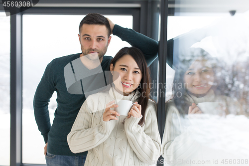 Image of multiethnic couple enjoying morning coffee by the window