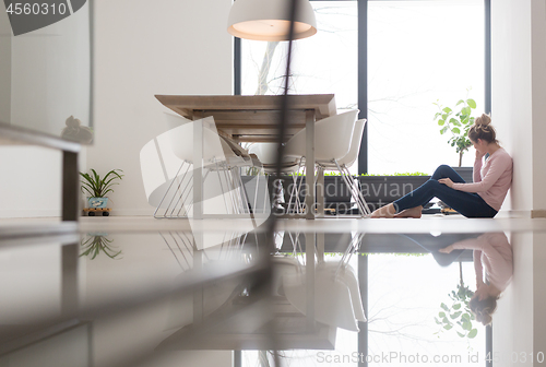Image of young woman using mobile phone on the floor