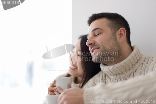 Image of multiethnic couple enjoying morning coffee by the window