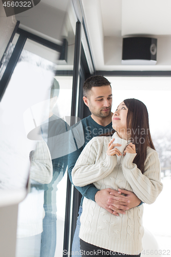 Image of multiethnic couple enjoying morning coffee by the window