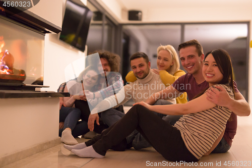 Image of multiethnic couples sitting in front of fireplace