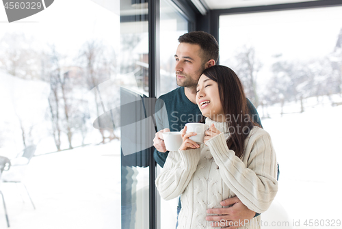 Image of multiethnic couple enjoying morning coffee by the window