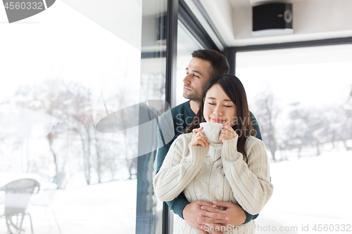 Image of multiethnic couple enjoying morning coffee by the window