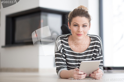 Image of woman using tablet computer in front of fireplace