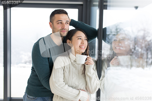 Image of multiethnic couple enjoying morning coffee by the window