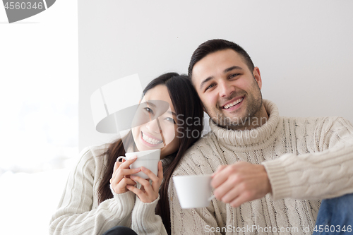 Image of multiethnic couple enjoying morning coffee by the window