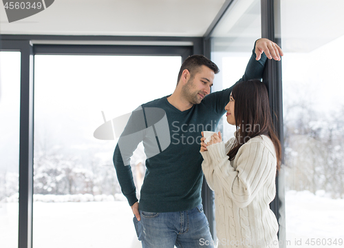 Image of multiethnic couple enjoying morning coffee by the window