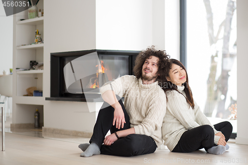 Image of happy multiethnic couple  in front of fireplace