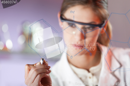 Image of Portrait of a confident female researcher in life science laboratory writing structural chemical formula on a glass board.