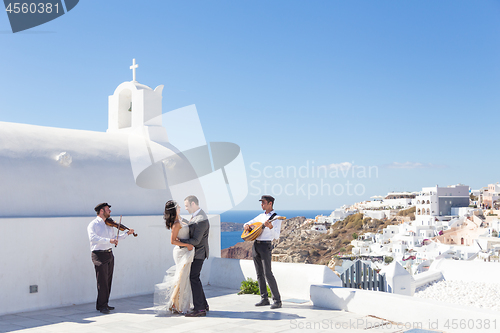 Image of Bride and groom dansing on wedding ceremony on Santorini island, Greece.