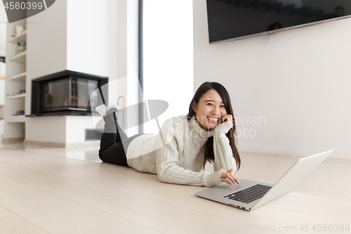 Image of young Asian woman using laptop on the floor