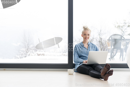 Image of woman drinking coffee and using laptop at home