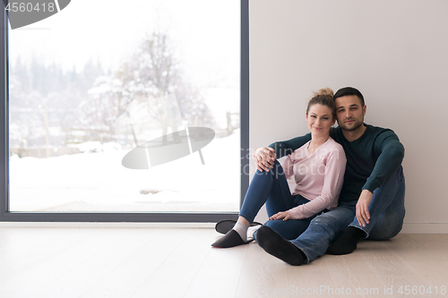 Image of young couple sitting on the floor near window at home