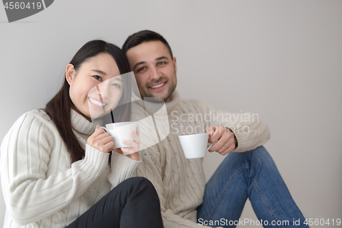 Image of multiethnic couple enjoying morning coffee by the window