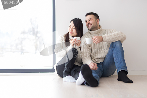 Image of multiethnic couple enjoying morning coffee by the window