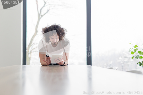 Image of young man using a tablet at home