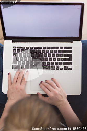 Image of young woman on sofa at home websurfing