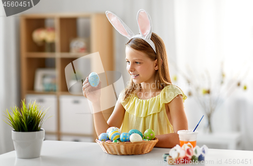 Image of happy girl with colored easter eggs at home