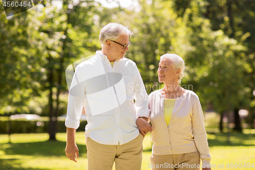 Image of happy senior couple walking at summer park