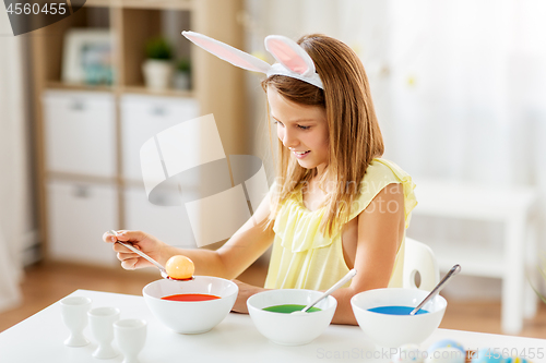 Image of girl coloring easter eggs by liquid dye at home