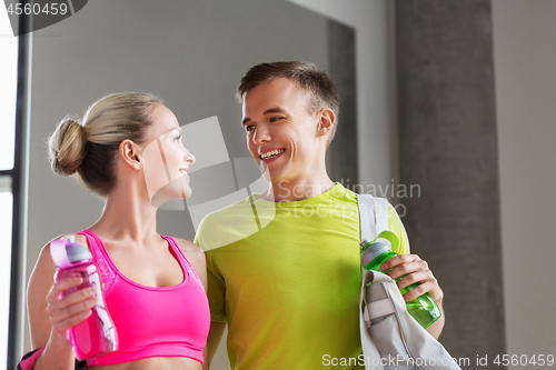 Image of sportive couple with water bottles and bag in gym