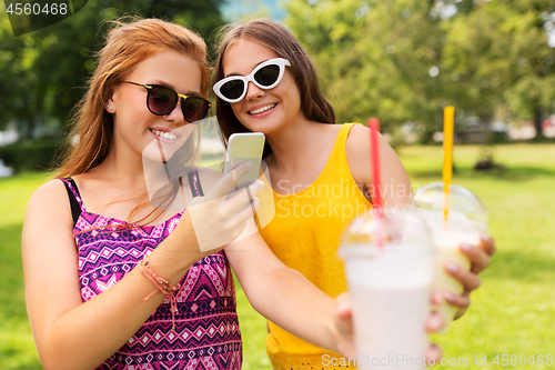 Image of teenage girls with smartphone and shakes in park