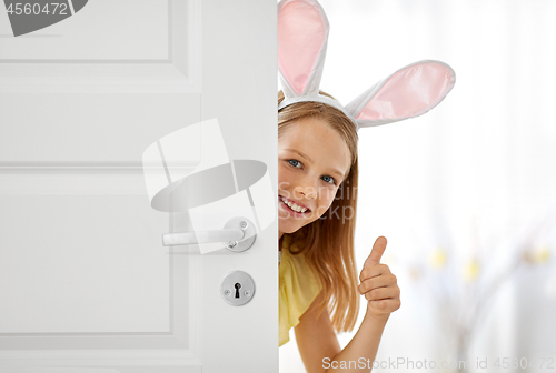 Image of happy girl with easter bunny ears peeking out door