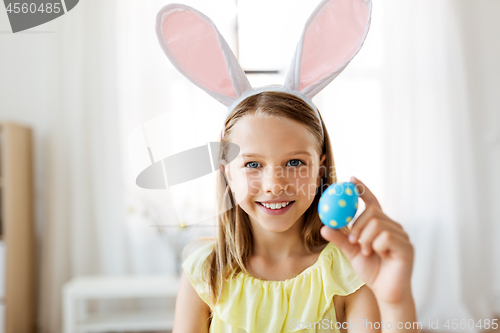 Image of happy girl with colored easter egg at home