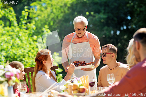 Image of family having dinner or barbecue at summer garden