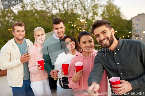 Image of friends with drinks taking selfie at rooftop party