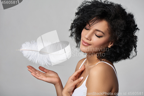 Image of Beautiful mixed race woman holding white ostrich feather