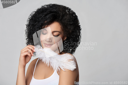 Image of Beautiful mixed race woman holding white ostrich feather