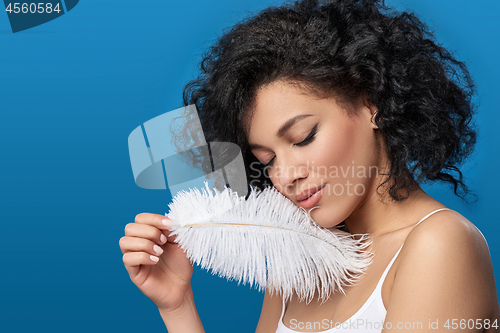 Image of Beautiful mixed race woman holding white ostrich feather