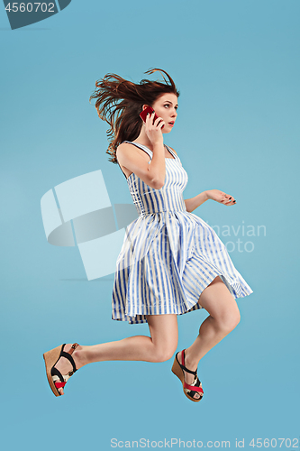 Image of Full length of pretty young woman with mobile phone while jumping