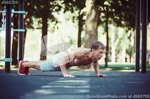 Image of Athlete doing exercises at stadium at park